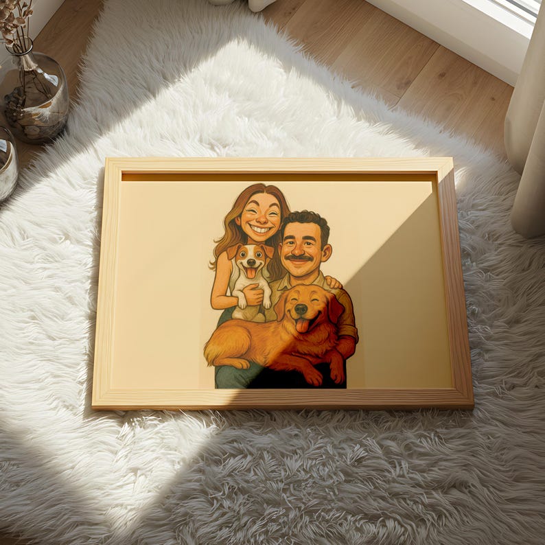 May include: A framed cartoon illustration of a smiling couple with two dogs. The artwork features a light wood frame and is set against a cream-colored background. The dogs are a golden retriever and a small terrier mix.