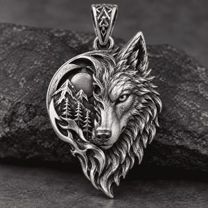 May include: A silver-toned pendant featuring a detailed wolf head profile integrated with a mountain landscape, pine trees, and a circular moon. The design includes intricate fur textures and a decorative bail at the top for attachment.