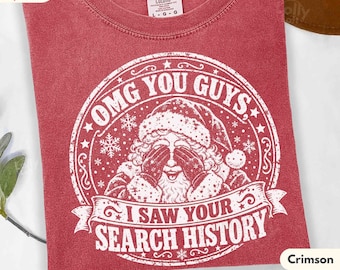 May include: A crimson red crew neck t-shirt featuring a white graphic of Santa Claus covering his eyes. The text reads OMG YOU GUYS, I SAW YOUR SEARCH HISTORY. The shirt has a Comfort Colors label at the neck and a distressed, vintage-style print.