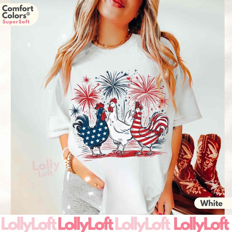 Pode incluir: Camiseta branca com um gr&aacute;fico de tr&ecirc;s galinhas com penas vermelhas, brancas e azuis. As galinhas est&atilde;o em p&eacute; em frente a um show de fogos de artif&iacute;cio. O texto "Comfort Colors" e "SuperSoft" est&aacute; impresso no canto superior esquerdo da imagem. O texto "White" est&aacute; impresso no canto inferior direito da imagem.