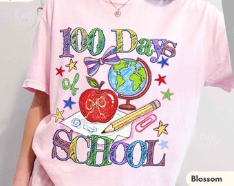 May include: A light pink t-shirt featuring a colourful graphic with the text 100 Days of School. The design includes a red apple, a globe, a pencil, a paper clip, a bow, and various stars in a scribbled, multi-coloured crayon style.