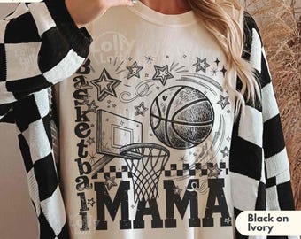 May include: An ivory t-shirt featuring a black graphic print of a basketball, a hoop, and stars. The text reads Basketball MAMA in a bold font. The shirt is worn under a black and white checkered cardigan. The image includes text that says choose your color combination and Black on Ivory.