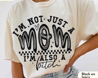 May include: Ivory-colored t-shirt with the text "I'M NOT JUST A MOM I'M ALSO A bitch" in black. The shirt has a crew neck and short sleeves. The text is in a bold, stylized font.