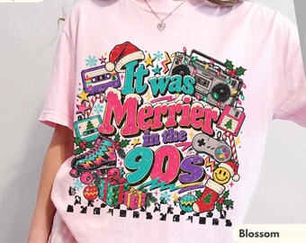 May include: A light pink t-shirt featuring a graphic print with the text It was Merrier in the 90s. The design includes a boombox, cassette tape, roller skate, video game controller, floppy disk, gifts, and a Christmas stocking.