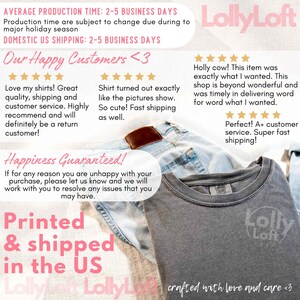 以下が含まれることがあります： Lolly Loftのロゴと「crafted with love and care」の文字が入ったグレーのTシャツが、青いジーンズの上に折りたたまれています。画像には、顧客レビューと発送に関するテキストも含まれています。