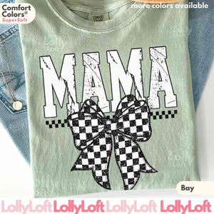 Op de afbeelding: Een lichtgroen t-shirt met het woord "MAMA" in grote witte blokletters. Een zwart-wit geblokte strik is onder het woord gecentreerd. Het shirt wordt op een denim achtergrond getoond.