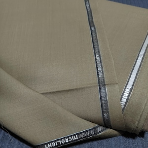 May include: A close-up of a folded piece of brown fabric with a black and silver trim. The trim has the word "MICROLIGHT" printed on it.