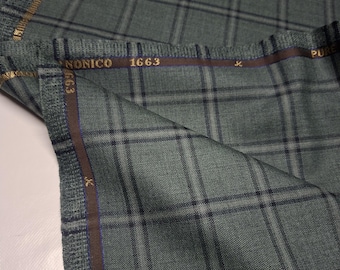 May include: A folded length of sage green fabric featuring a dark charcoal plaid pattern. The selvage edge is brown with gold text reading NONICO 1663 and PURE WOOL. The textile has a visible woven texture and is draped to show the pattern clearly.