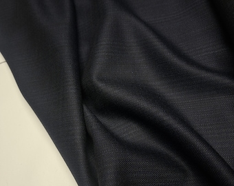 May include: Close-up of a dark navy blue fabric with a subtle woven texture. The material is draped, showing folds and shadows. The fabric appears to be a medium weight, suitable for apparel or home decor projects.