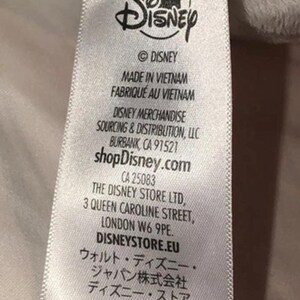 May include: A white tag with the Disney logo and text. The tag includes the text "MADE IN VIETNAM", "shopDisney.com", and addresses for Disney merchandise and The Disney Store Ltd.