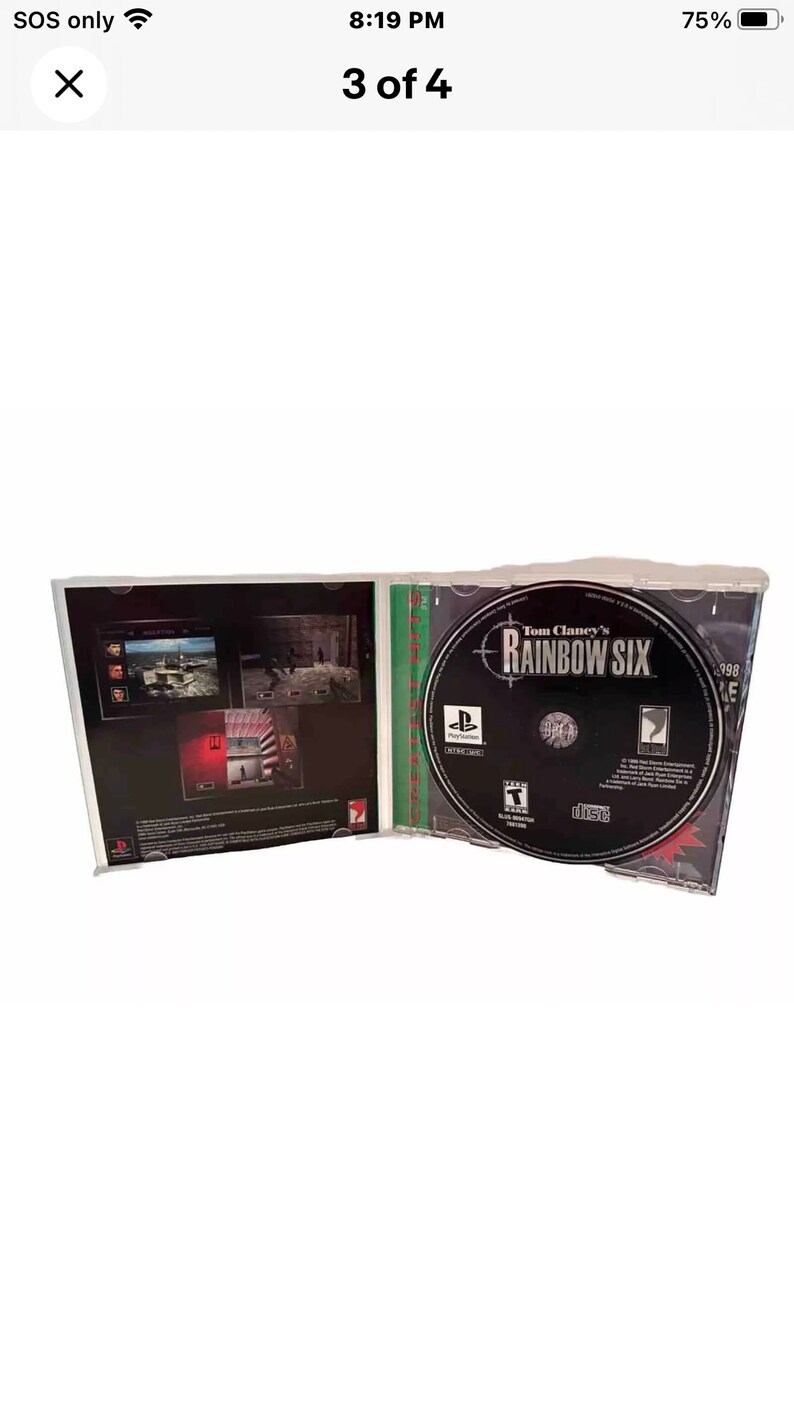 May include: A PlayStation game case for Tom Clancy's Rainbow Six. The case is open and the disc is visible. The disc is black with a green and white target design. The text "Tom Clancy's Rainbow Six" is printed in white on the disc.