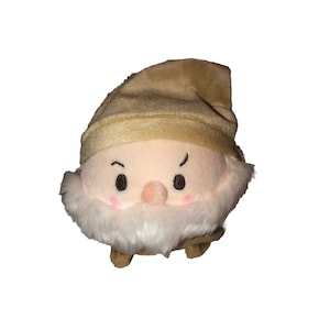 May include: A plush toy of Grumpy from Snow White and the Seven Dwarfs. The toy is brown and white and has a grumpy expression on its face.