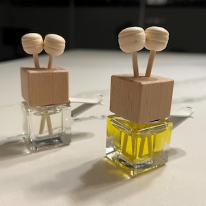 May include: Two small glass bottles with wooden tops and wooden sticks with round wooden balls on the ends. The bottles are filled with a clear liquid and a yellow liquid.