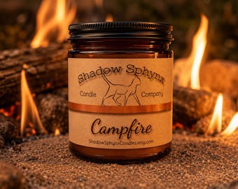 Könnte beinhalten: Ein braunes Kerzenglas mit schwarzem Deckel und beigem Papieretikett. Das Etikett zeigt eine Strichzeichnung einer Katze, den Text Shadow Sphynx Candle Company, das Wort Campfire und die Webadresse ShadowSphynxCandles.etsy.com.