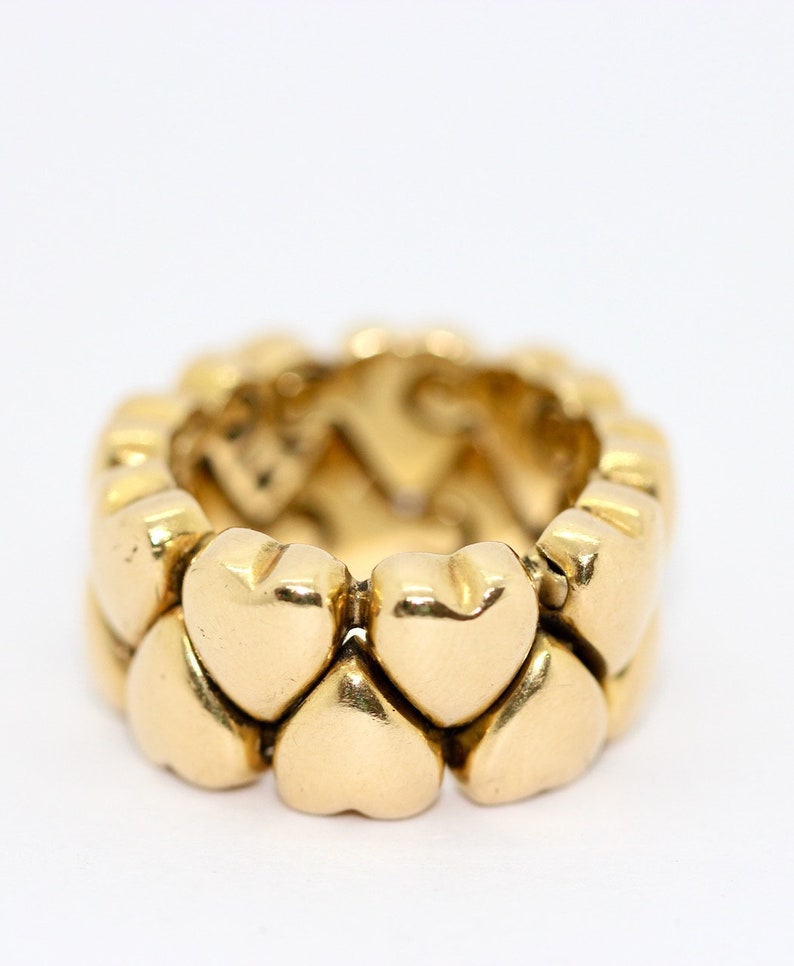 May include: A gold heart-shaped ring with a band made of interlocking hearts