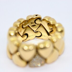 May include: A gold heart-shaped ring with a row of diamonds on the bottom. The ring is engraved with the words 'CARTIER' and 'DO1357'.