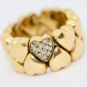May include: A gold ring with a heart-shaped design. The ring is made up of multiple heart-shaped pieces, with a single heart in the center that is set with small diamonds.