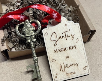 Könnte beinhalten: Ein Holzschild mit dem Text "Santa's Magic Key to William's house" und ein goldfarbener Schlüssel mit einer Weihnachtsmannfigur. Schlüssel und Schild befinden sich in einer braunen Box mit zerknülltem Papier.
