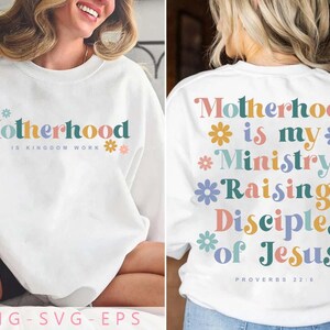 May include: White sweatshirt with the text "Motherhood is Kingdom Work" on the front, and "Motherhood is my Ministry Raising Disciples of Jesus" on the back. The text is in various colors with flower accents. Proverbs 22:6 is printed on the back.