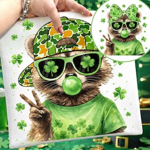 May include: A white pillow featuring a raccoon wearing green sunglasses with shamrock lenses, a green t-shirt, and a camouflage hat. The raccoon is blowing a green bubble and giving a peace sign. The pillow is decorated with shamrocks.