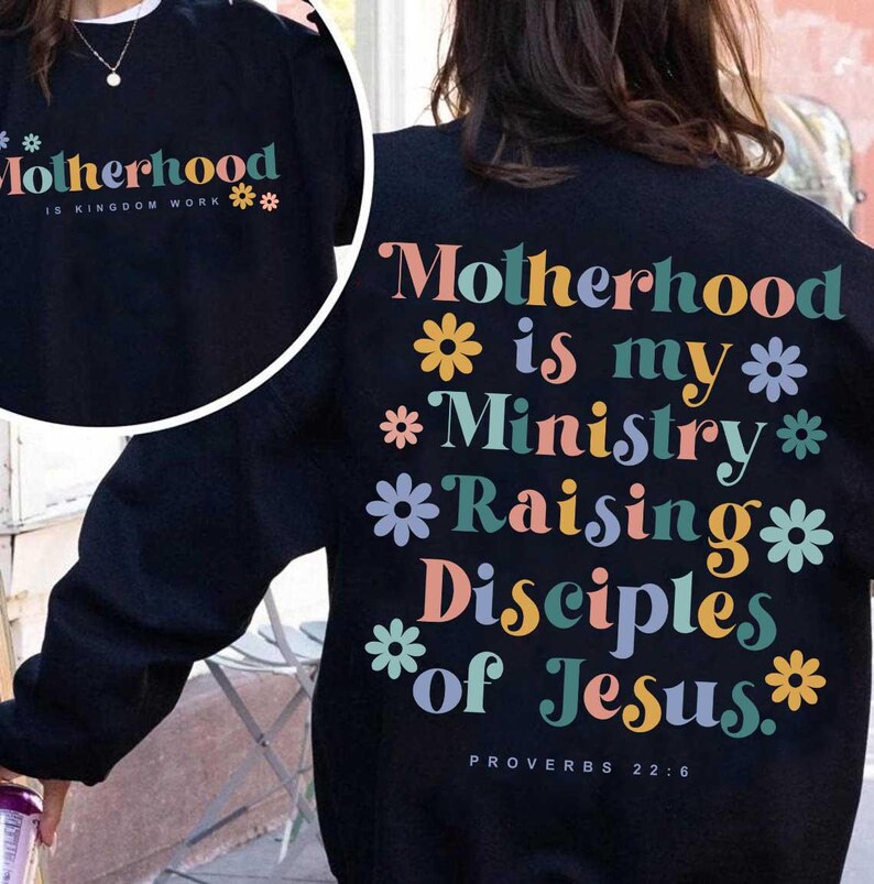 May include: Black sweatshirt with the text "Motherhood is my Ministry Raising Disciples of Jesus" in colorful letters and flower graphics. The text "Proverbs 22:6" is at the bottom. A smaller image shows the text "Motherhood is Kingdom Work".