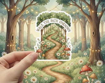 May include: A sticker featuring a whimsical forest scene with a winding path, mushrooms, and daisies. The text "WALK THE PATH UNKNOWN" arches across the top. The sticker is held in a hand, with a watercolor-style background of trees and fairy lights.