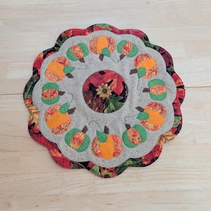 Pumpkin Candle Mat/Table Topper with scalloped edges.  Hand Made, quilted and appliqued.  14 inches in diameter.