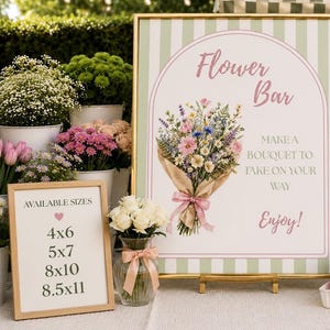 May include: A large rectangular sign with a green and white striped border, gold frame, and text reading Flower Bar, Make a bouquet to take on your way, Enjoy. A smaller sign lists available sizes 4x6, 5x7, 8x10, and 8.5x11 in inches.