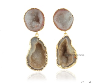 Puede incluir: Un par de pendientes de tono dorado con una piedra druzy en forma de lágrima. Las piedras son de color marrón claro con un interior blanco. Los pendientes son una pieza llamativa y serían perfectos para una ocasión especial.