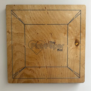May include: A wooden box kit with a heart logo and the text "The Pink Paper Box".