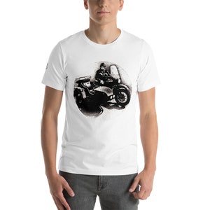 May include: A white t-shirt with a black and white illustration of a person riding a motorcycle with a sidecar.