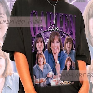 May include: A black t-shirt with a graphic print of a woman with the text "Garten Ina" on it. The graphic features multiple images of the woman in different poses. The t-shirt is being modeled by a person wearing black sunglasses.