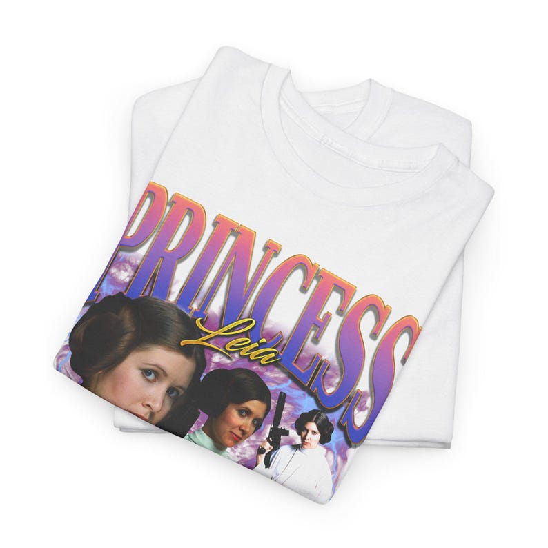 May include: White t-shirt with a graphic print of Princess Leia from Star Wars. The graphic features a colorful, retro-style font with the text "Princess Leia" and images of Princess Leia in different poses.