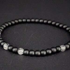 Könnte beinhalten: Ein schwarzes Armband mit durchsichtigen Perlen, die dazwischen liegen.