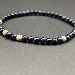 Könnte beinhalten: Ein blaues und weißes Perlenarmband mit einem elastischen Band. Die Perlen sind klein und rund, mit einer gesprenkelten blauen Farbe und ein paar weißen Perlen.