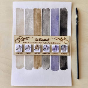 Könnte beinhalten: Aquarellfarbenset mit einer Auswahl an neutralen Farben, darunter Patina Earth, Tin Gray und Indian Black. Das Set enthält ein Holzschild mit der Aufschrift "So Neutral" und einen Pinsel.
