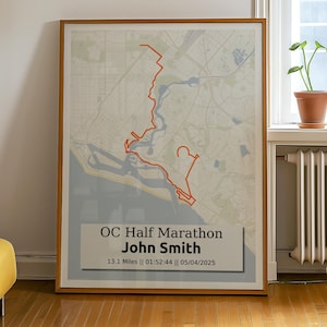 May include: A framed map of a running route with the text "OC Half Marathon John Smith 13.1 Miles | 01:32:44 | 05/04/2025" printed below the map.