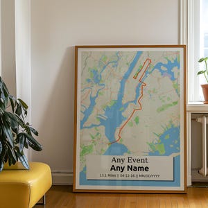 May include: A framed map of New York City with a red line marking a route. The map has a blue background and green and brown land features. The frame is light brown wood. The text on the map reads "Any Event Any Name 13.1 Miles | 04.12.16 | MM/DD/YYYY".