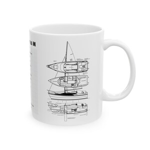 Puede incluir: Una taza de cerámica blanca con un dibujo en blanco y negro de un velero. El dibujo muestra el barco desde diferentes ángulos, incluyendo la cubierta, el interior y el casco. El texto "Catalina 25 M" está impreso en el lateral de la taza.