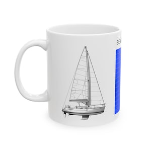 May include: White ceramic mug featuring a detailed line drawing of a sailboat. The design includes the boat's hull, mast, and sails. A blue vertical stripe is on the right side of the mug. The mug has a curved handle.
