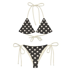 Könnte beinhalten: Ein schwarz-weißer Bikini mit weißen Trägern und Punkten. Das Oberteil ist im Dreieckstil und das Unterteil im knappen Stil.