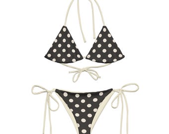 Könnte beinhalten: Ein schwarz-weißer Bikini mit weißen Trägern und Punkten. Das Oberteil ist im Dreieckstil und das Unterteil im knappen Stil.