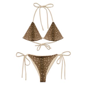 May include: A two-piece bikini set featuring a brown and white spotted pattern, reminiscent of deer fur. The top is a triangle style with halter ties, and the bottoms have side ties. The bikini is made of a soft, lightweight material.