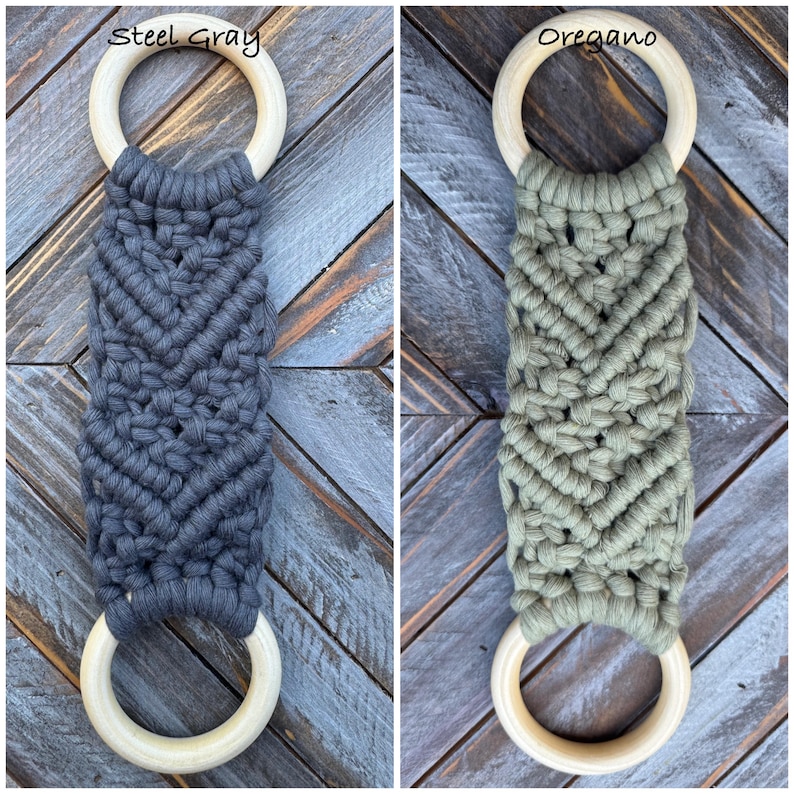 Pu&ograve; includere: Due decorazioni da parete in macram&egrave; con un motivo a nodi chevron. Uno &egrave; grigio acciaio e l'altro verde origano. Ogni pezzo presenta un anello in legno chiaro e liscio nella parte superiore e inferiore, collegati dal design in corda annodata.