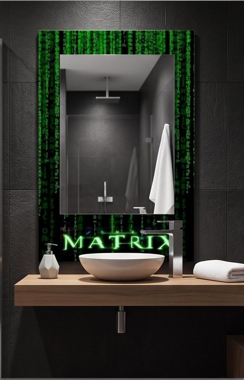 K&ouml;nnte beinhalten: Ein rechteckiger Wandspiegel mit einem schwarzen Rahmen, der mit gr&uuml;nen digitalen Codemustern und dem Wort MATRIX in einer leuchtend gr&uuml;nen Schrift am unteren Rand verziert ist. Der Spiegel reflektiert ein Badezimmer mit Duschkopf und Handtuch.