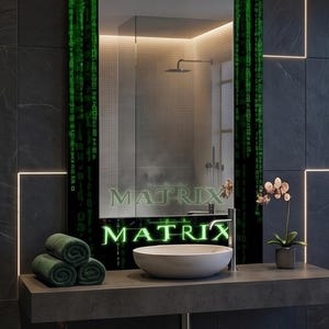 K&ouml;nnte beinhalten: Ein rechteckiger Wandspiegel mit einem schwarzen Rahmen, der mit gr&uuml;nen digitalen Codemustern und dem Wort MATRIX in leuchtend gr&uuml;nen Buchstaben verziert ist. Der Spiegel reflektiert ein Badezimmer mit einem wei&szlig;en Waschbecken.