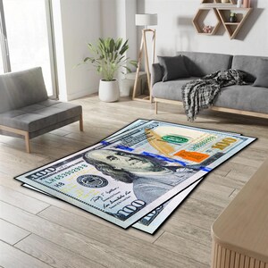 Könnte beinhalten: Ein Teppich mit einer Nahaufnahme eines 100-Dollar-Scheins der USA mit dem Porträt von Benjamin Franklin und dem Text "THE UNITED STATES OF AMERICA" und "ONE HUNDRED DOLLARS".