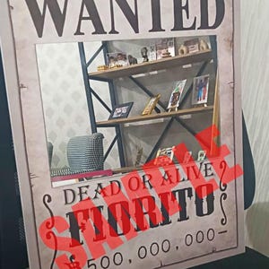 K&ouml;nnte beinhalten: Ein rechteckiges Poster mit beigem, verwittertem Hintergrund und dem Wort WANTED in gro&szlig;en schwarzen Buchstaben oben. Unter einem zentralen rechteckigen Ausschnitt steht der Text DEAD OR ALIVE, FIORITO und 500.000.000 mit rotem Stempel.