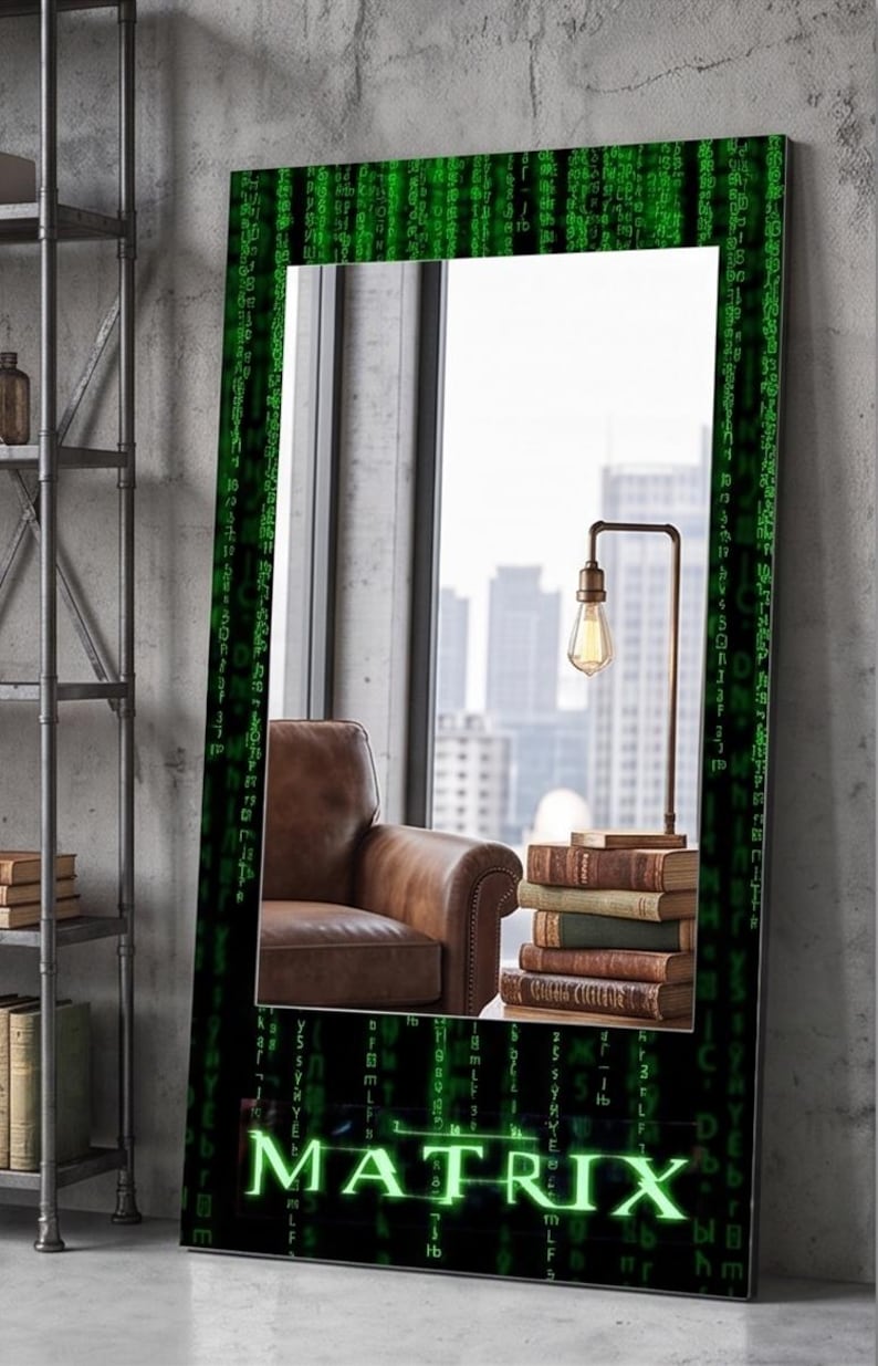 K&ouml;nnte beinhalten: Ein rechteckiger Standspiegel mit einem schwarzen Rahmen, der mit gr&uuml;nen digitalen Codemustern und dem Wort MATRIX in leuchtend gr&uuml;nen Buchstaben am unteren Rand verziert ist. Die Spiegelfl&auml;che zeigt einen braunen Ledersessel, B&uuml;cher und eine Lampe.