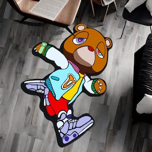 May include: A colorful rug featuring a cartoon bear wearing a blue and yellow jacket, red pants, and purple sneakers. The bear has a brown face with a purple and red eye.